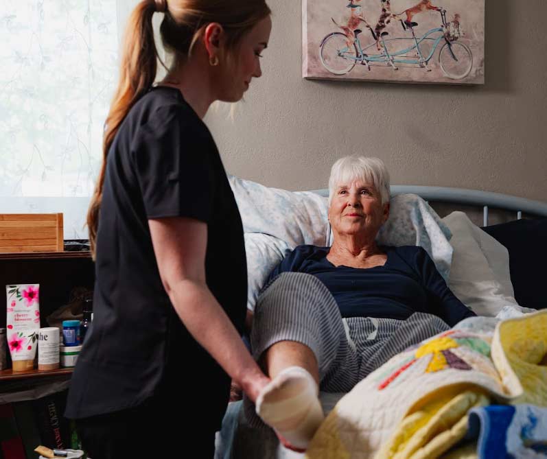 A compassionate caregiver providing personal care and grooming assistance to a senior woman in a brightly lit bathroom to ensure hygiene and safety