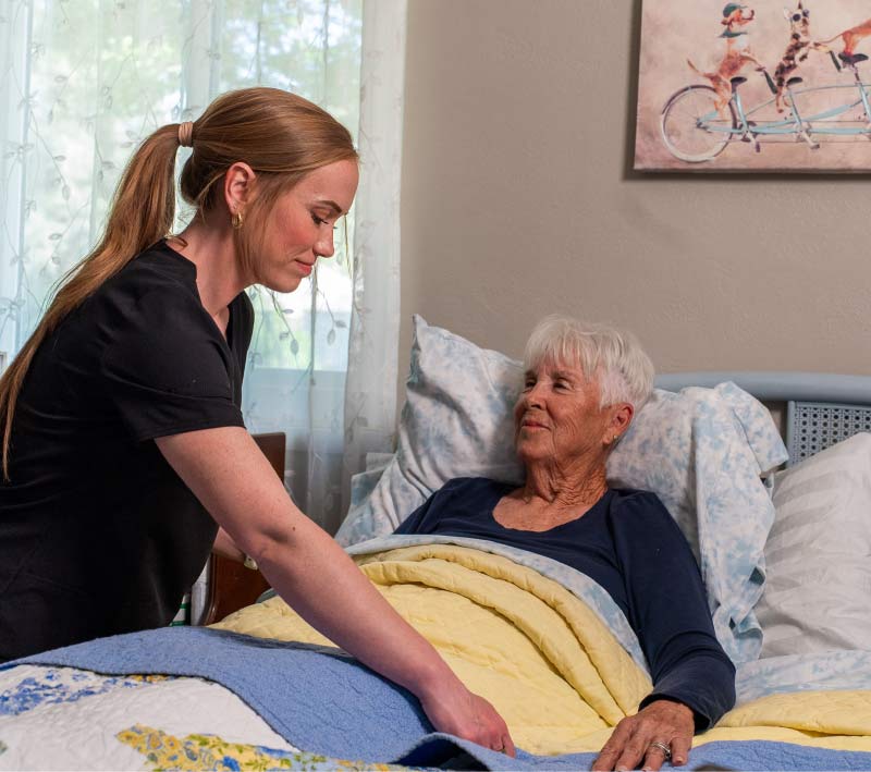 An Amdal In-Home Care in Tulare, CA professional providing specialized bed-side support and comfort to a senior client to reduce the risk of bed-sores and ensure proper circulation